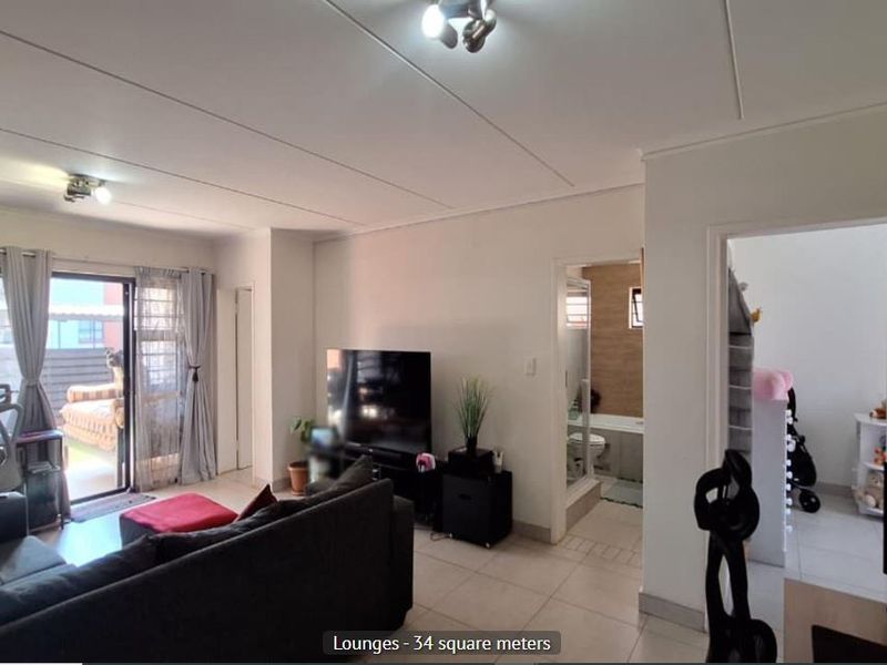 Spacious living area featuring tiled flooring and a large sliding glass door providing access to the outdoor space.