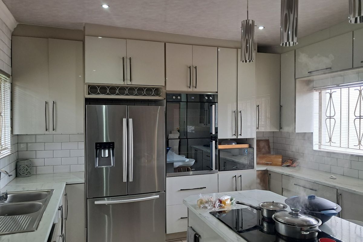 Modern kitchen featuring high-gloss cabinetry, marble-look countertops, subway tile backsplash, and integrated appliances including a built-in oven and induction cooktop.