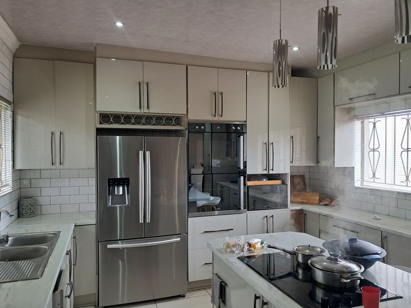 Modern kitchen featuring high-gloss cabinetry, marble-look countertops, subway tile backsplash, and integrated appliances including a built-in oven and induction cooktop.