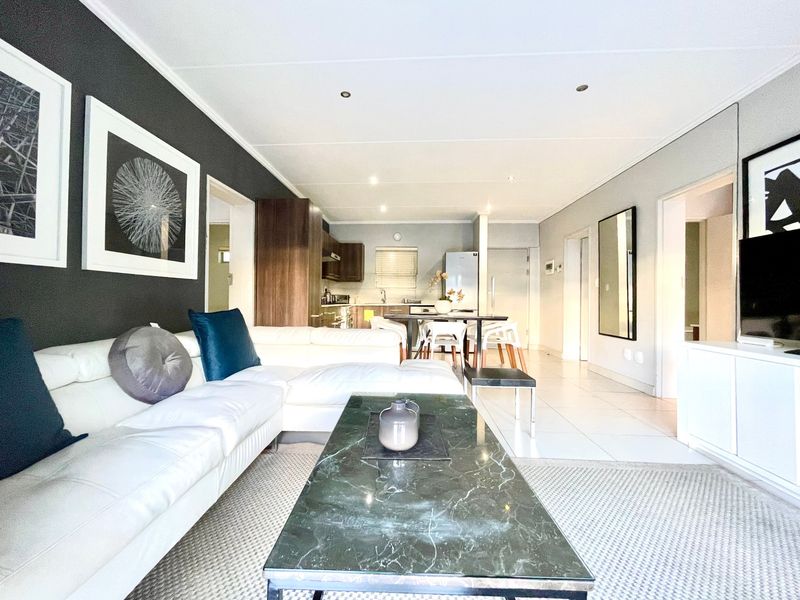 Spacious open-plan living and dining area featuring modern tiled flooring, recessed lighting, and a seamless transition into the functional kitchen space.