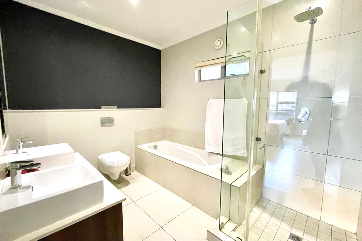 Modern bathroom featuring a double vanity, built-in bathtub, and a separate glass-enclosed shower with a rain shower head.