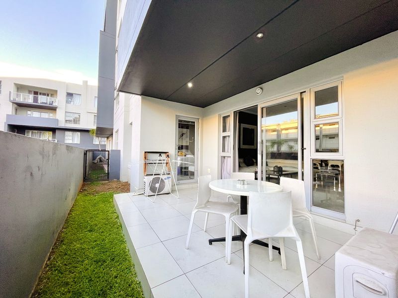 A modern ground-floor patio featuring tiled flooring, recessed lighting, and direct access to the living area through large sliding glass doors.