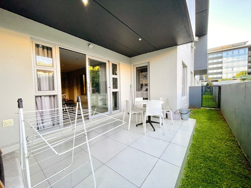 A covered patio area featuring large format floor tiles, recessed lighting, and direct access to the interior living space through sliding glass doors.