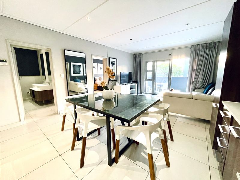 Spacious open-plan living and dining area featuring modern tiled flooring, recessed lighting, and seamless access to a private balcony.