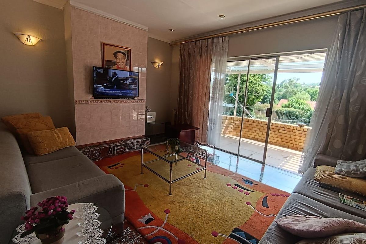 A comfortable living room featuring tiled flooring, a tiled fireplace surround, and large sliding glass doors that open onto an outdoor patio area.