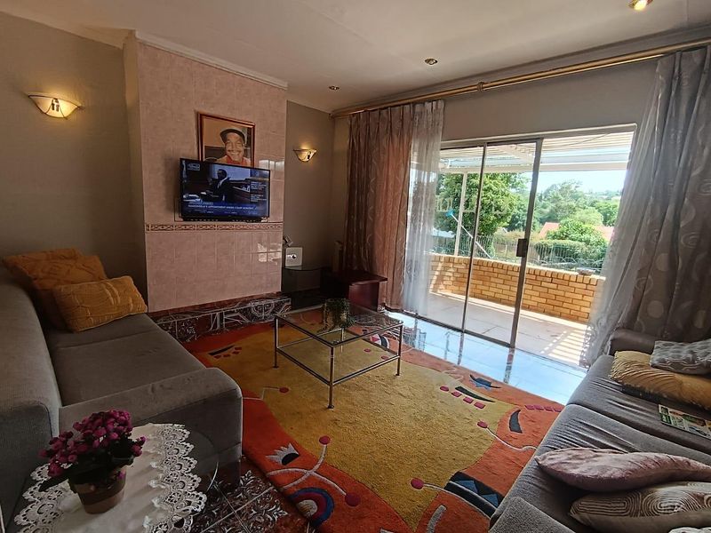 A comfortable living room featuring tiled flooring, a tiled fireplace surround, and large sliding glass doors that open onto an outdoor patio area.