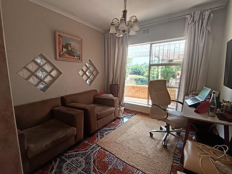 A living area featuring decorative glass block wall inserts, tiled flooring, and a classic chandelier, with natural light provided by a large window.