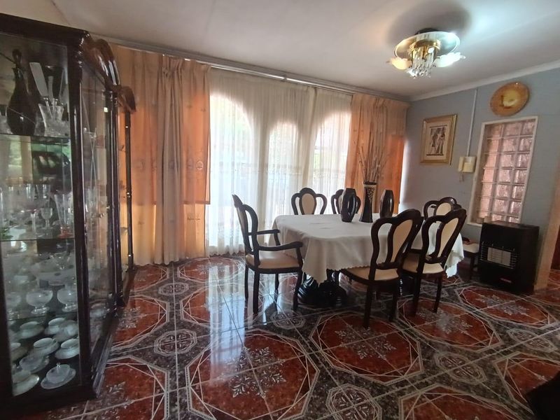 A dining room featuring patterned ceramic tile flooring, a glass block window, and a central ceiling light fixture.