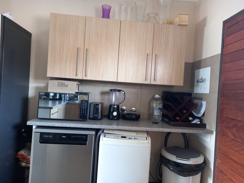 A functional kitchen area featuring light wood-tone cabinetry, granite countertops, and space for an integrated dishwasher and laundry appliance.