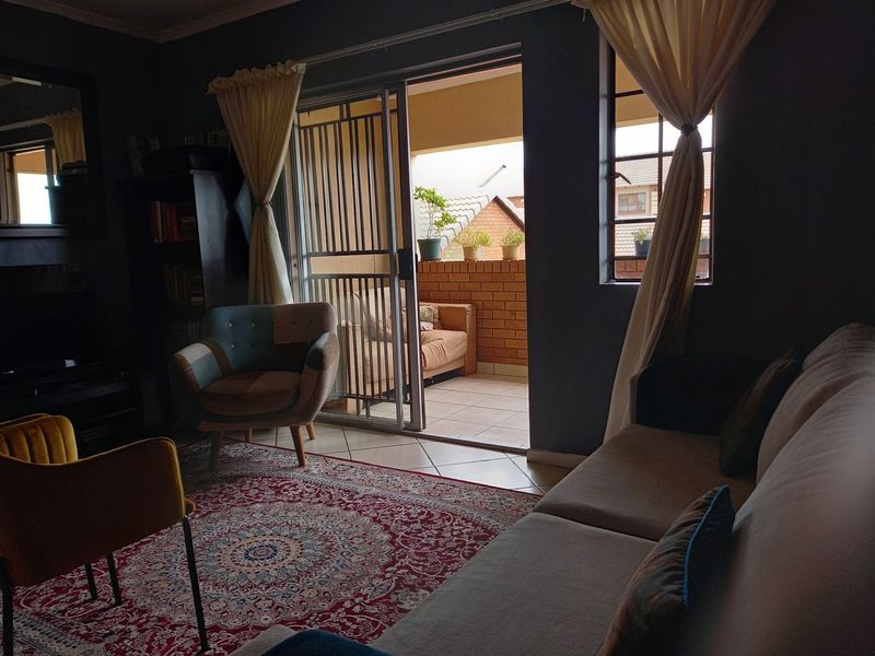 A cozy living room featuring tiled flooring and a sliding glass door that opens onto a private balcony.