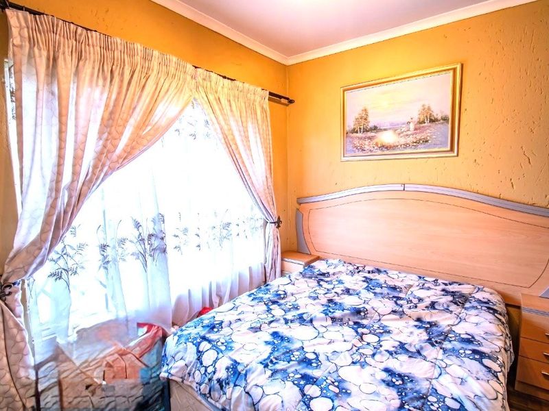 A bedroom featuring textured walls and a window with curtain fixtures, providing a functional space for rest.