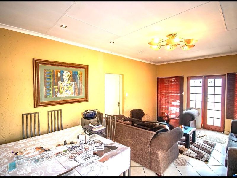 Open plan living and dining area featuring tiled flooring and french doors leading to the exterior, with potential for cosmetic updates.