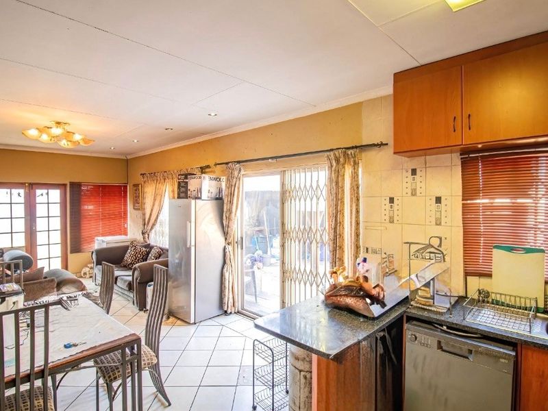 Open-plan living and kitchen area featuring tiled flooring, built-in cabinetry, and direct access to the outdoor space via a sliding glass door.