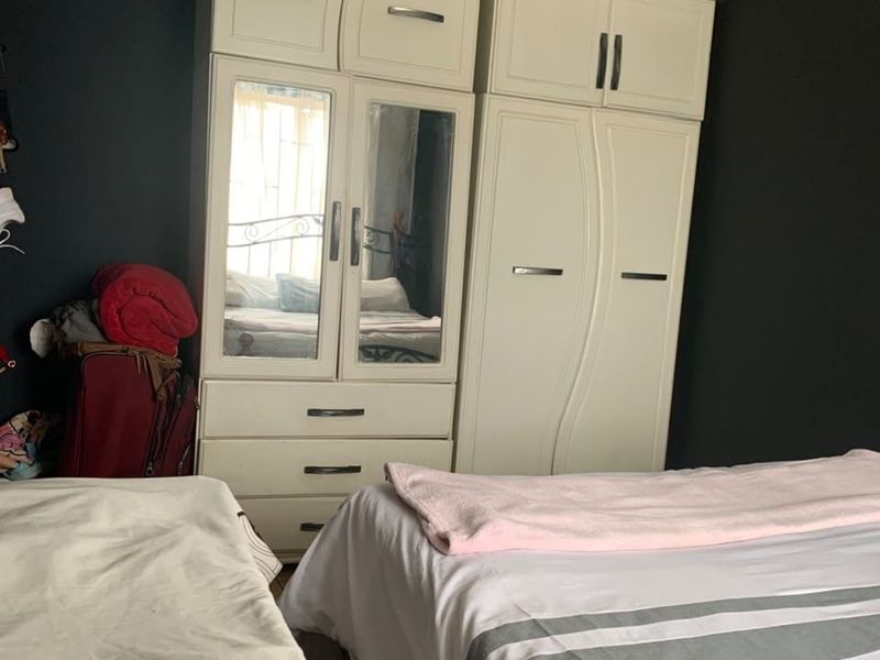 A bedroom featuring built-in cupboards and recessed downlights, currently showing signs of ceiling wear and requiring maintenance.