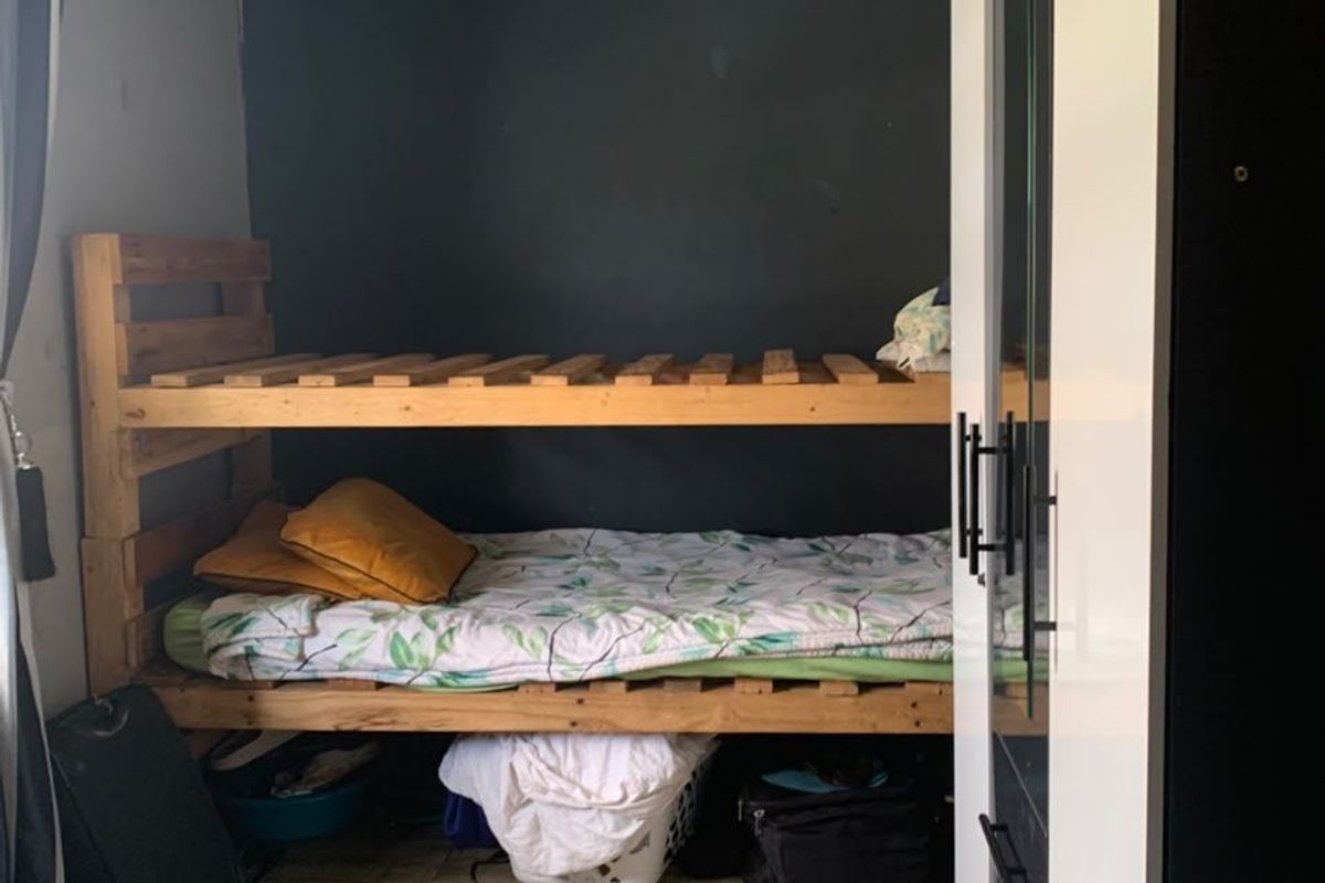 A compact bedroom featuring tiled flooring, a built-in wardrobe, and a dark accent wall, offering potential for modernization and improved layout.