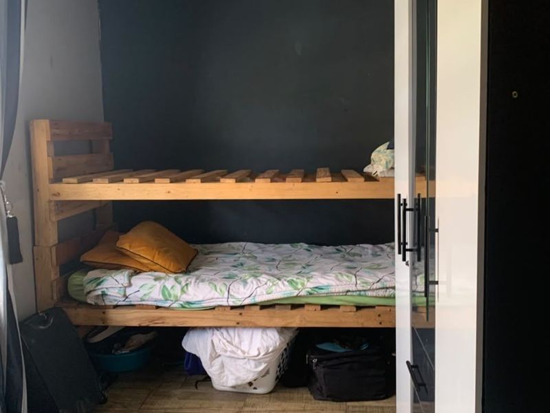 A compact bedroom featuring tiled flooring, a built-in wardrobe, and a dark accent wall, offering potential for modernization and improved layout.