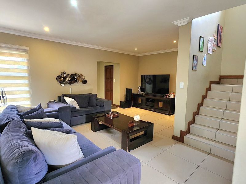 Spacious living room featuring tiled flooring, recessed lighting, and a staircase leading to the upper level.