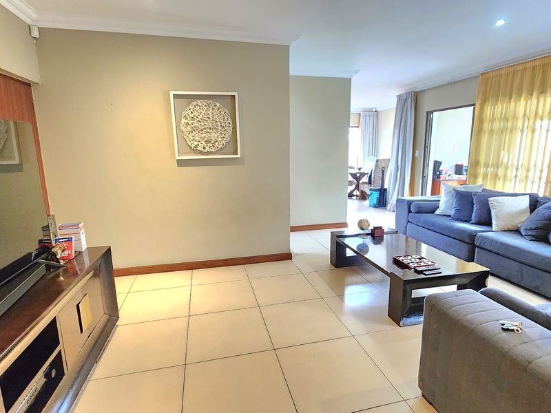 Spacious living room featuring neutral tiled flooring, recessed lighting, and large sliding doors that provide access to the adjoining area.