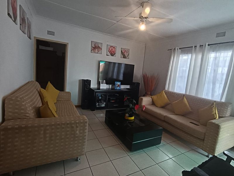 A comfortable living room featuring tiled flooring and a ceiling fan, providing a functional and well-lit space for relaxation.