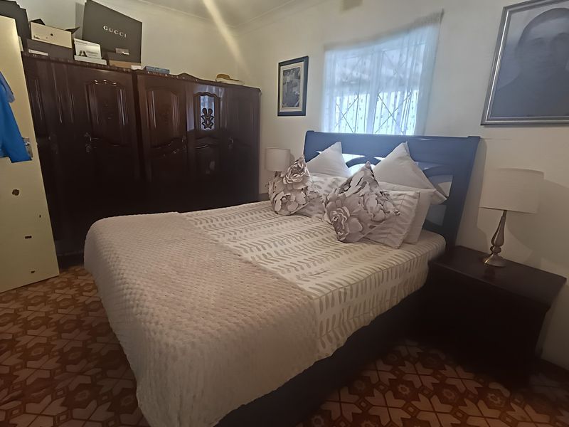 A bedroom featuring patterned flooring, a window with a security gate, and decorative coving.