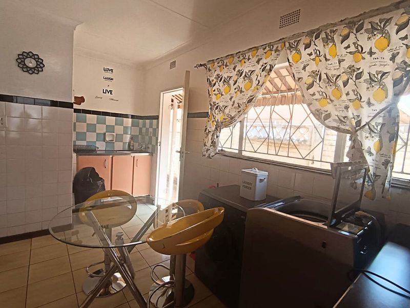 Functional laundry area featuring tiled flooring, built-in cabinetry with sink, and tiled splashbacks, providing a practical space for household utility tasks.
