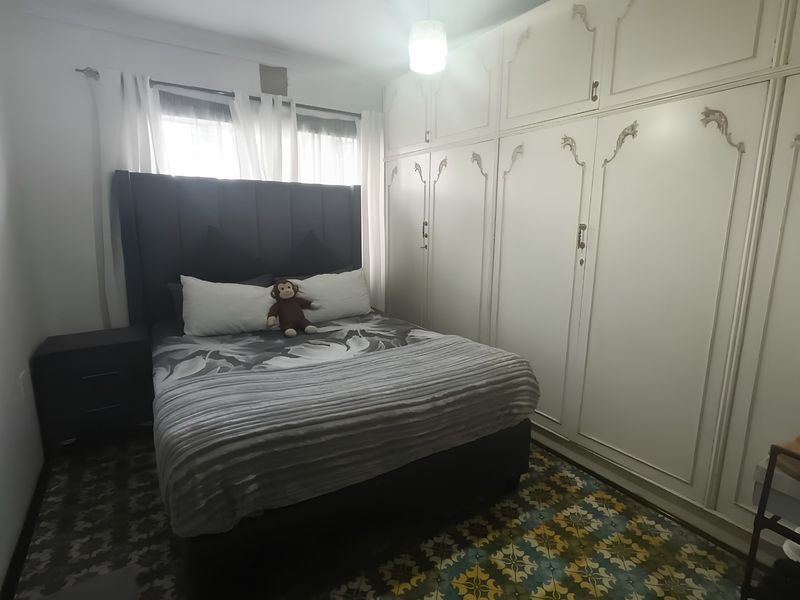 A bedroom featuring built-in cupboards and decorative patterned floor tiles, offering a functional space with classic storage solutions.