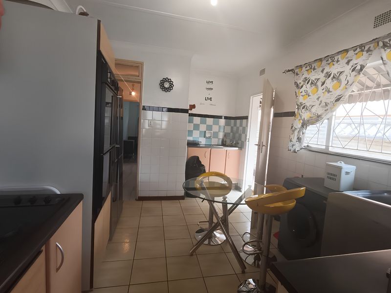 A functional kitchen featuring built-in cabinetry, tiled splashbacks, and integrated oven, offering a practical layout with space for a small dining area.