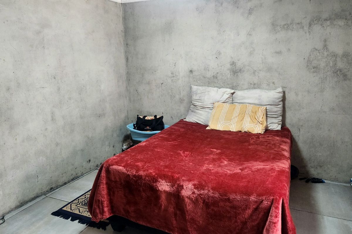 A bedroom featuring tiled flooring and unfinished concrete-style walls with decorative ceiling cornicing.