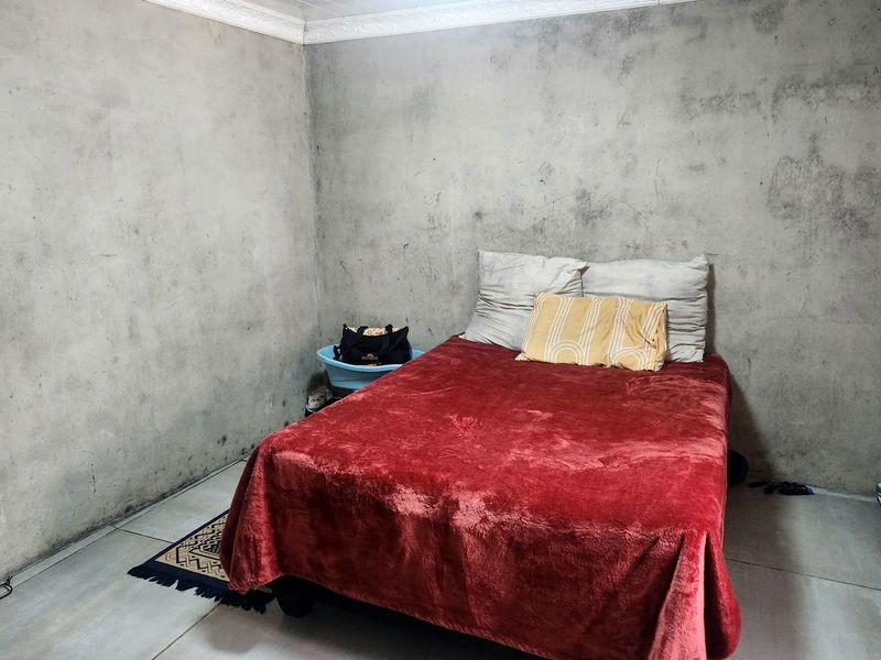 A bedroom featuring tiled flooring and unfinished concrete-style walls with decorative ceiling cornicing.