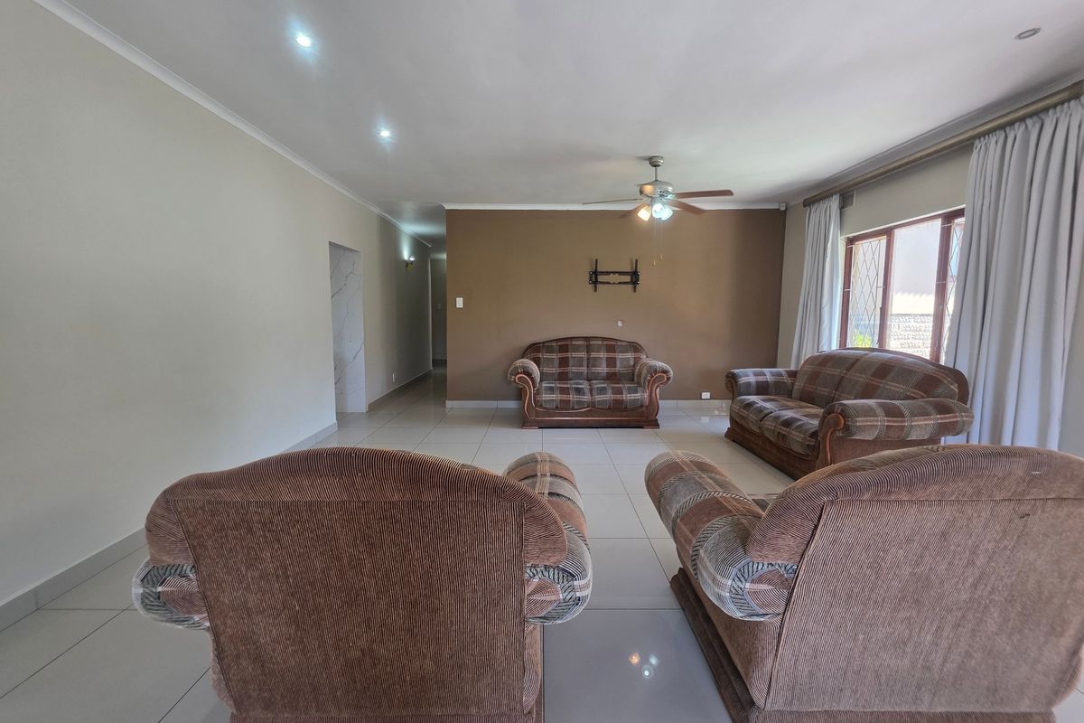 Spacious living room featuring neutral wall tones, tiled flooring, recessed lighting, and a ceiling fan, offering a versatile layout for comfortable family living.