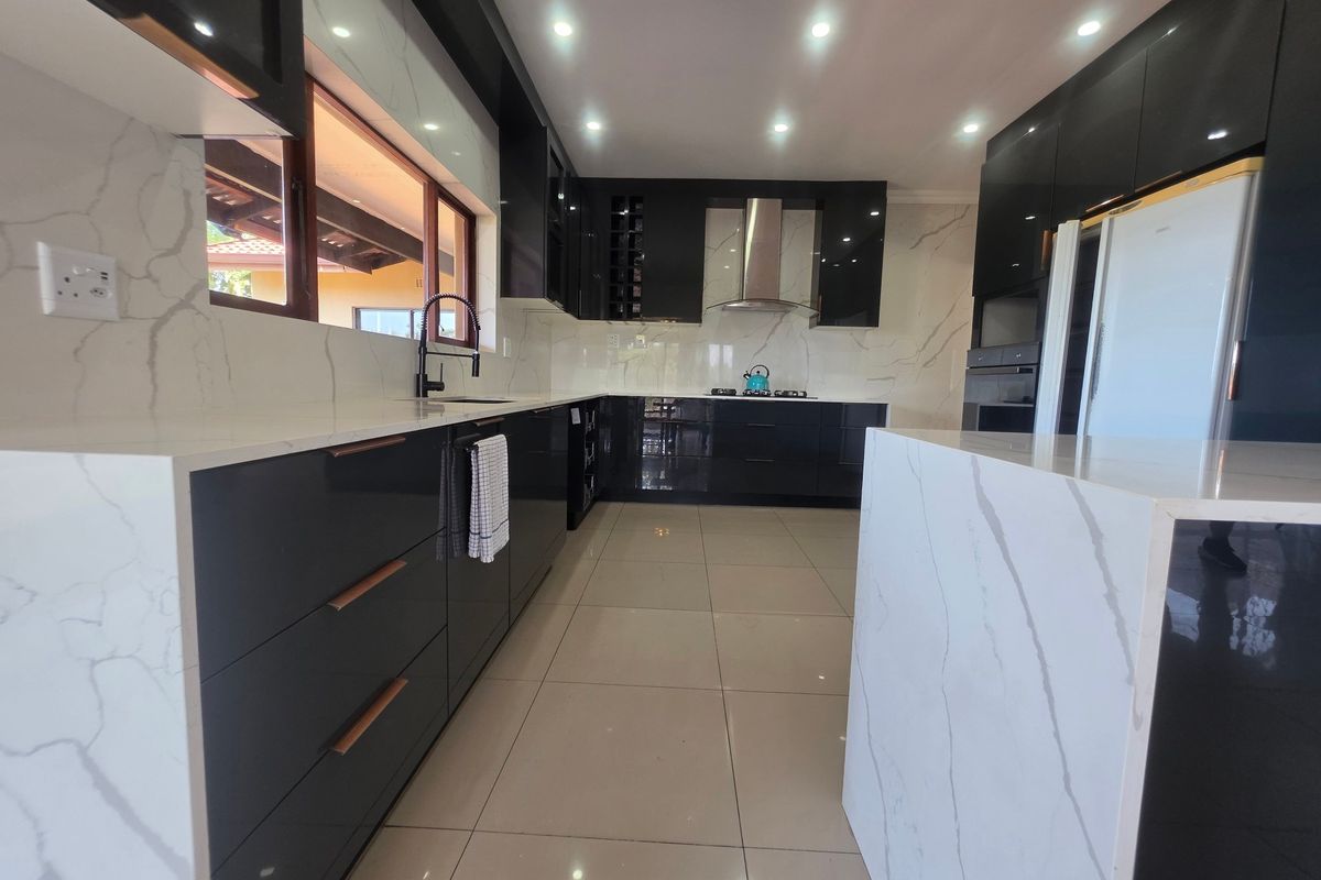 Modern kitchen featuring high-gloss black cabinetry, marble-look quartz countertops, integrated appliances, and sleek recessed lighting.