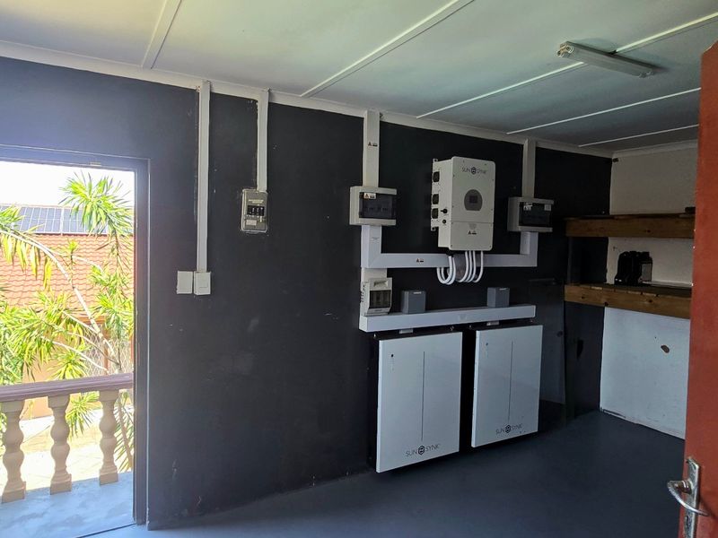 Utility room featuring a modern solar power installation with inverter and dual battery storage system, providing efficient energy management.