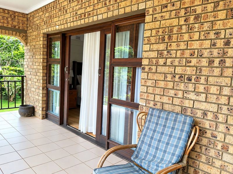 A covered patio area featuring face brick walls, tiled flooring, and large sliding glass doors providing access to the interior.