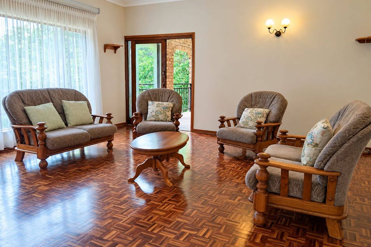 A spacious living room featuring polished parquet flooring, neutral walls, and a sliding glass door providing access to an outdoor patio area.