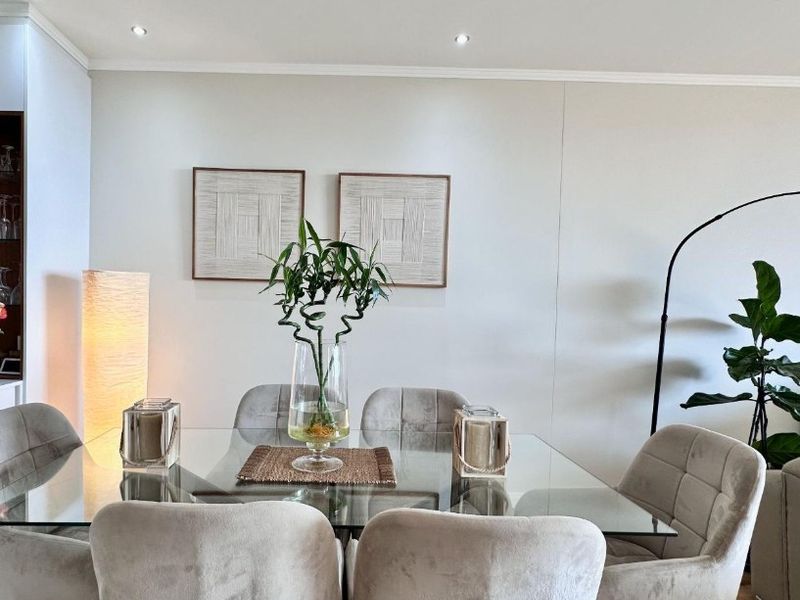 A well-lit dining area featuring recessed ceiling downlights and decorative coving, providing a clean and neutral backdrop for formal dining.