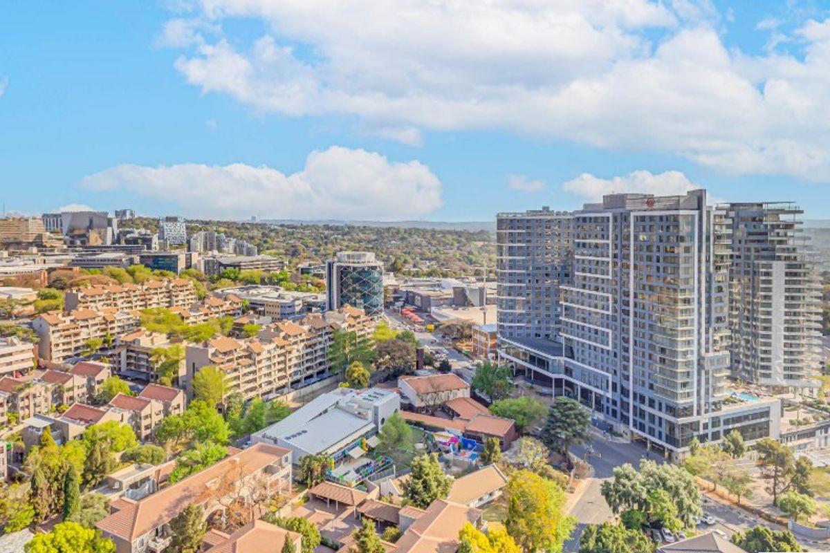 An elevated aerial view showcasing the surrounding urban landscape, neighborhood density, and modern high-rise apartment developments.