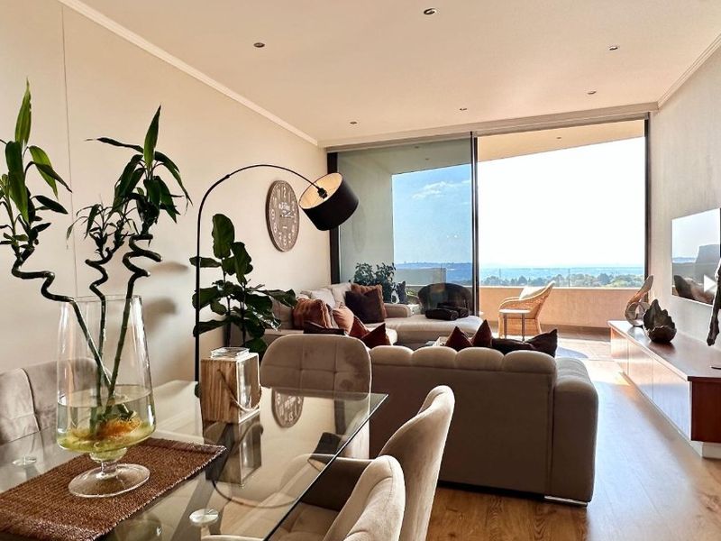 Bright open-plan living and dining area featuring modern laminate flooring, recessed lighting, and large sliding glass doors leading to a spacious balcony with views.