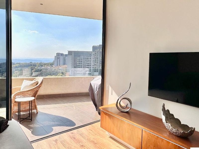 Modern living room featuring laminate flooring and large sliding doors opening onto a private balcony with expansive city views.