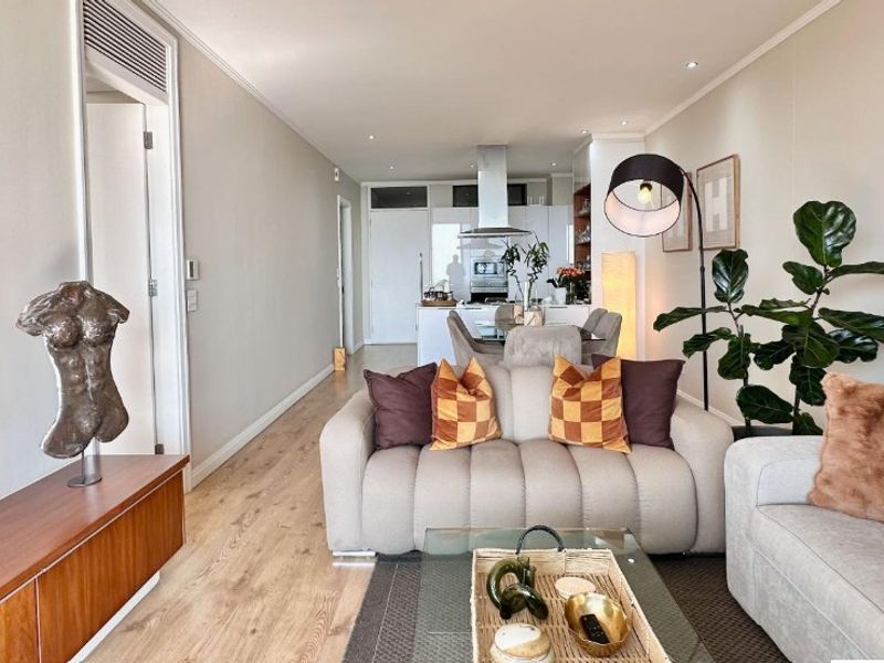 Modern open-plan living area featuring laminate flooring, recessed lighting, and a sleek kitchen with a central island and integrated extractor fan.