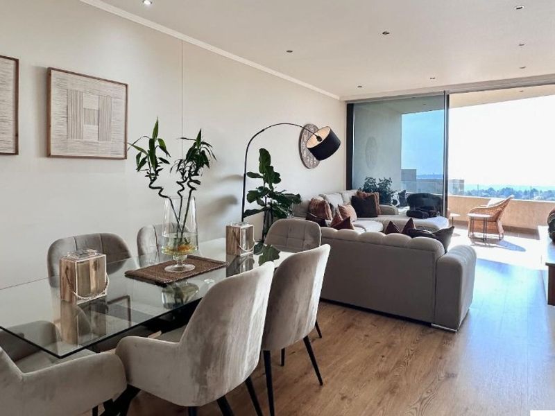 Spacious open-plan living and dining area featuring modern laminate flooring, recessed lighting, and large sliding glass doors leading to a private balcony.
