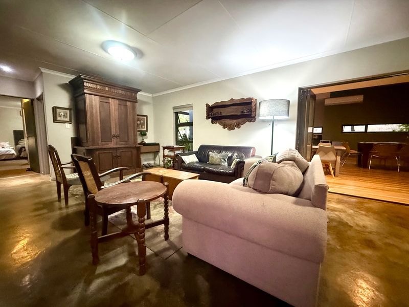 A spacious living room featuring polished concrete floors and bi-fold doors leading to an adjacent dining area.