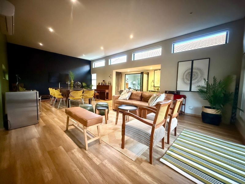 Spacious open-plan living and dining area featuring modern laminate flooring, recessed lighting, and high-level clerestory windows providing ample natural light.