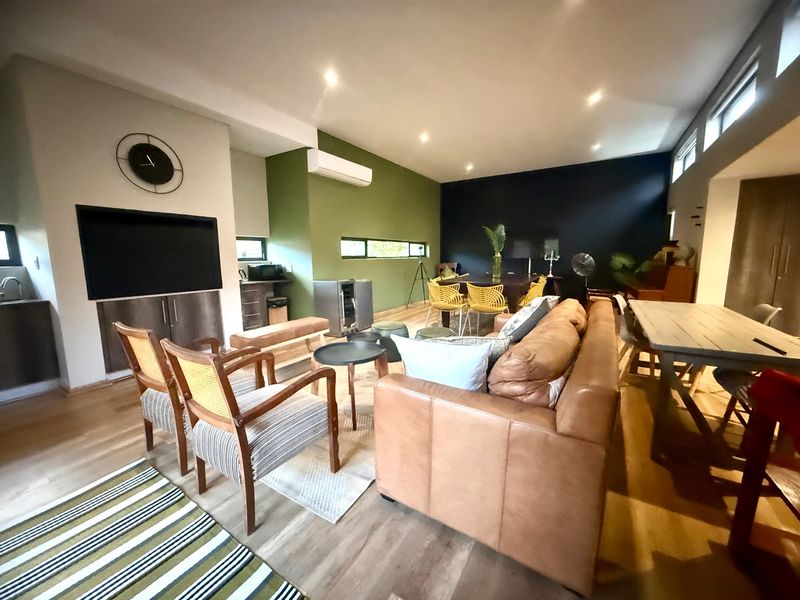 Spacious open-plan living and dining area featuring modern laminate flooring, recessed lighting, and a split-system air conditioner with contemporary accent walls.
