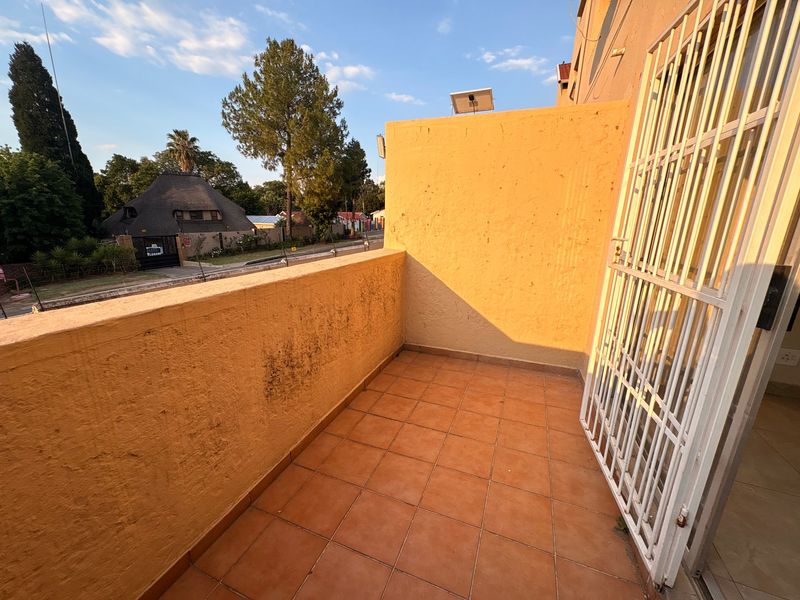 An open balcony featuring tiled flooring and a security gate, offering an outdoor space with potential for enhancement.