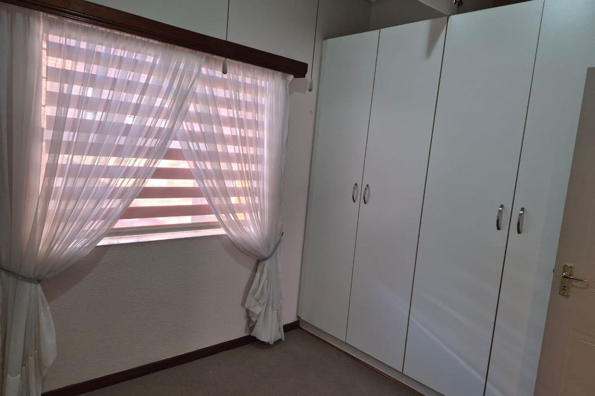 A clean, empty bedroom featuring neutral carpeted flooring and ample built-in cupboard storage space.