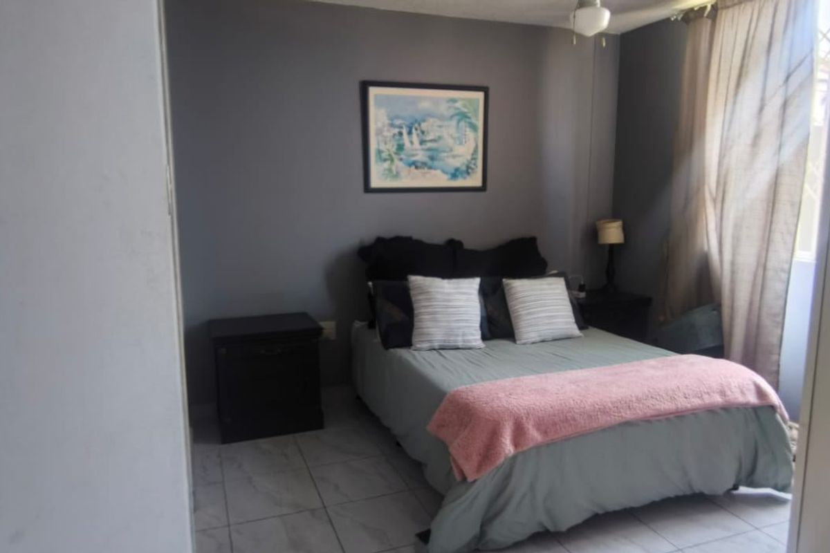 A bedroom featuring tiled flooring and neutral grey walls, offering a functional space with natural light.