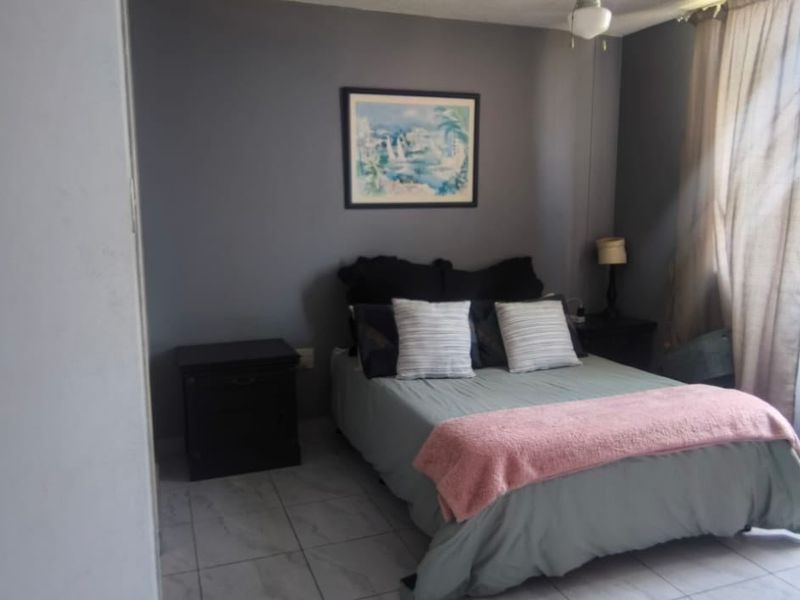 A bedroom featuring tiled flooring and neutral grey walls, offering a functional space with natural light.