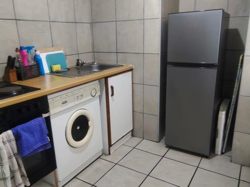 Compact kitchen featuring tiled walls and flooring, laminate countertops, built-in stove and oven, and integrated sink area.