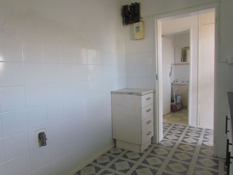 A functional laundry area featuring tiled splashbacks, built-in cabinetry, and direct access to an adjacent bathroom space.