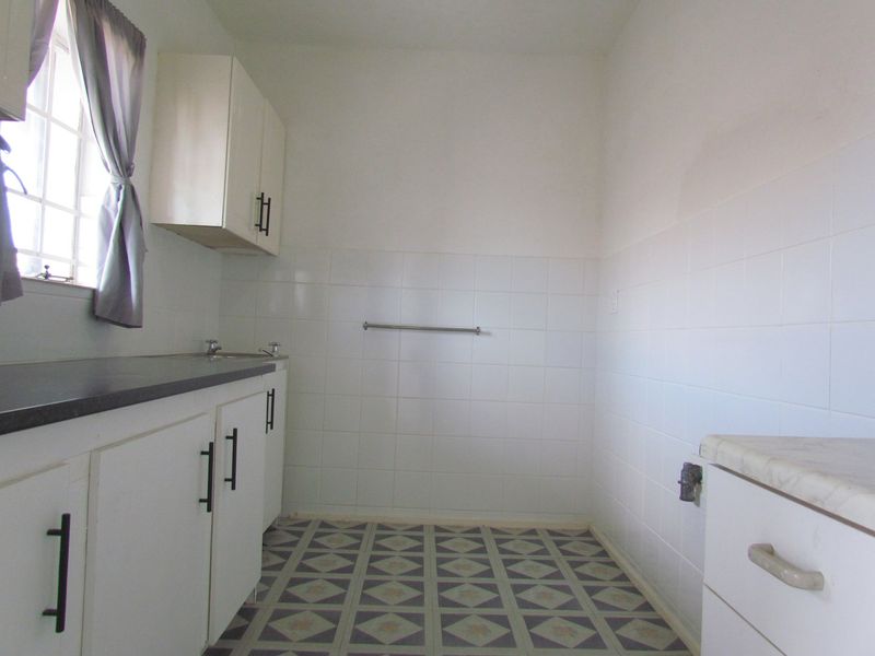 A functional laundry area featuring built-in cabinetry, tiled splashbacks, and dedicated plumbing connections for appliances.